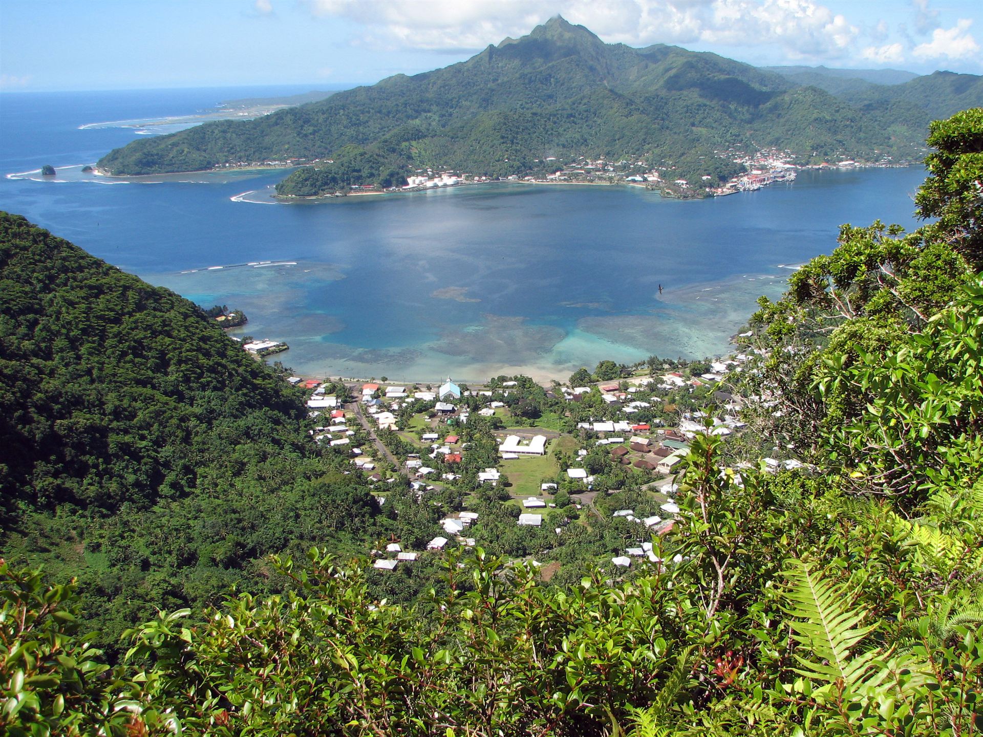 Aerial view of Pago Pago Harbor, American Samoa, ringed by lush green mountains.